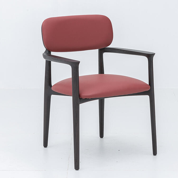 A person sitting on a concrete surface by the water, wearing a cream colored long-sleeve top and orange shorts, with long dark hair in a braid, viewed from behind